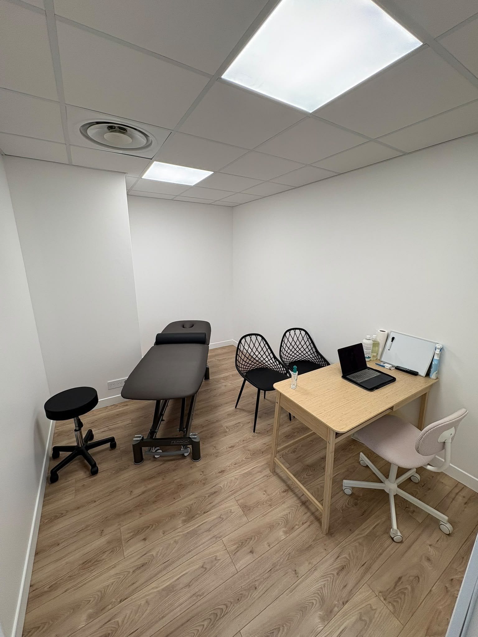 Salle de soins individuelle avec table électrique, bureau et deux chaises
