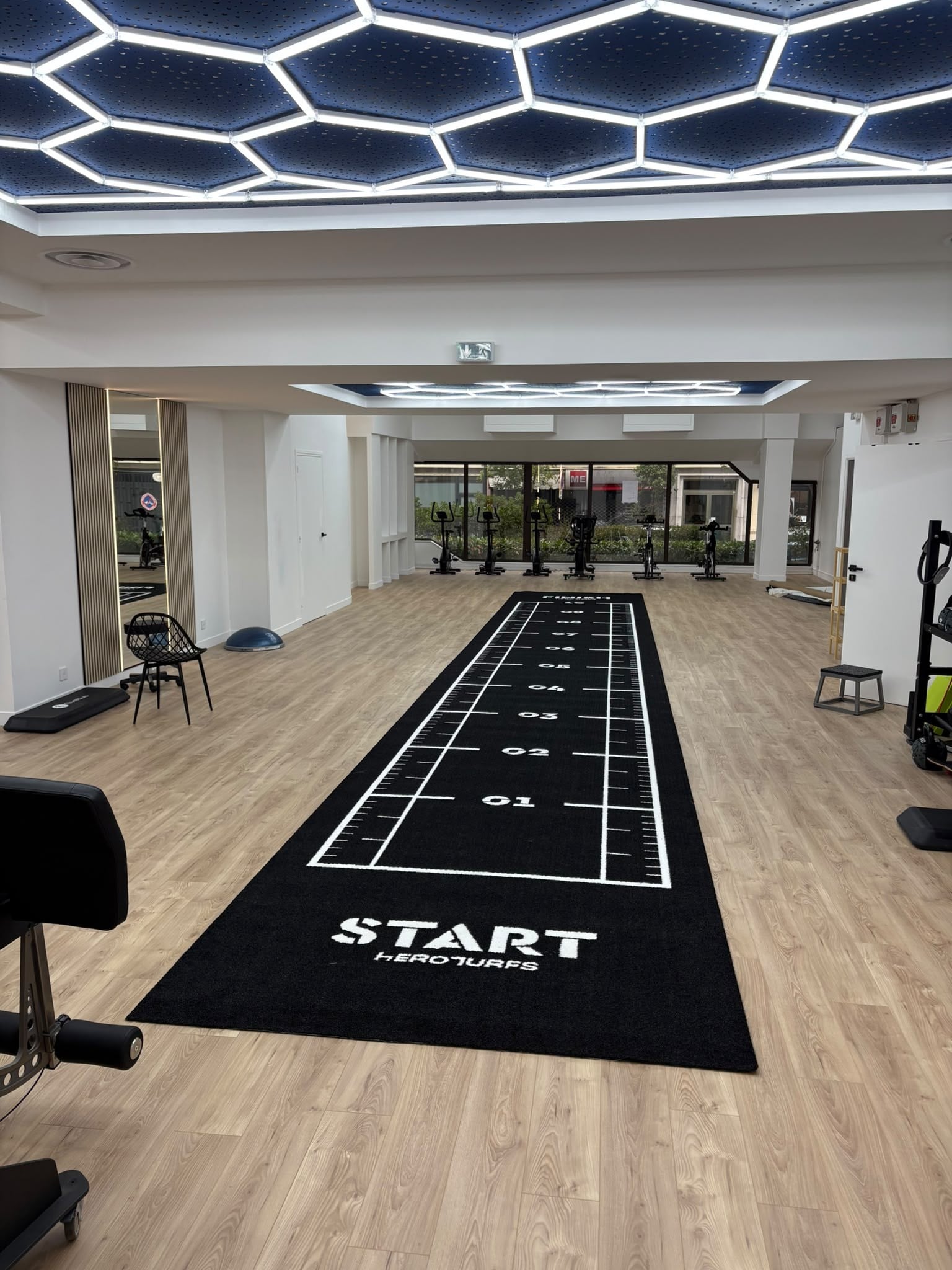 Plateau technique : piste, vélos devant les baies vitrées et plafond hexagonal